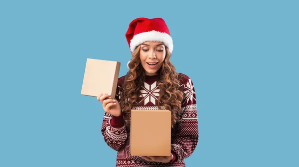 Sorpresa de invierno. Mujer bastante milenaria en traje de Navidad apertura caja de regalo en fondo de estudio azul — Foto de Stock