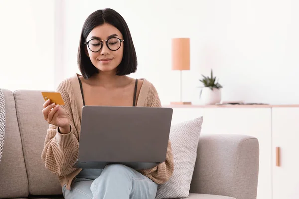 Asian woman making purchases sitting with pc on couch — Stock Photo, Image