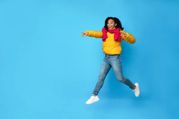 Excitada senhora africana apontando dedos pulando posando sobre fundo azul — Fotografia de Stock