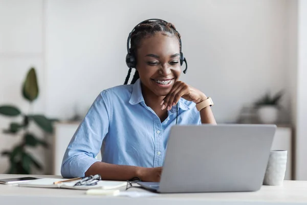 Afstandsonderwijs. Jonge zwarte vrouw in headset kijken Webinar op laptop — Stockfoto