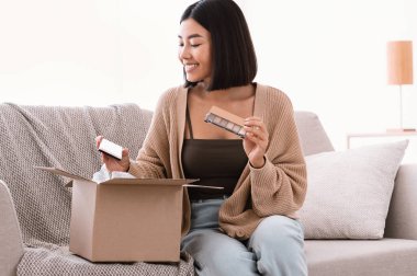 Güzel kutulu paketleri açan mutlu Asyalı kadın.