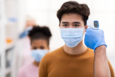 Asyalı Adam İçin Sıcaklık İncelemesi yapan Sıhhiye İşçisi