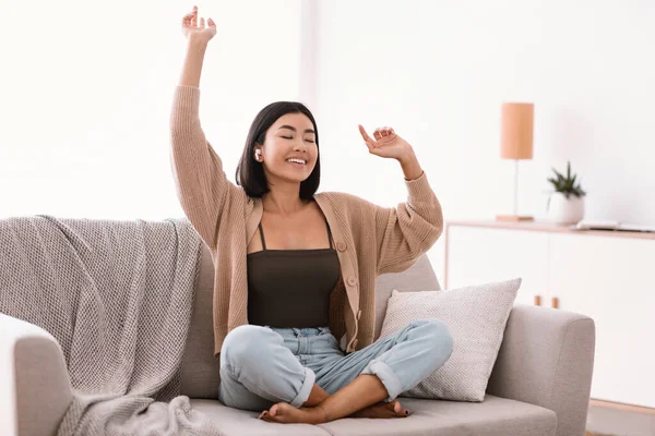 Mujer asiática escuchando música y bailando en el sofá — Foto de Stock