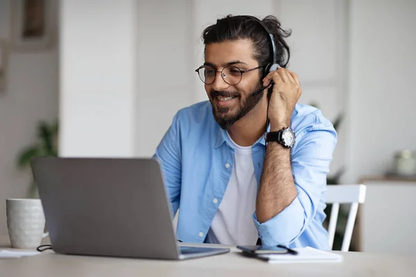 Sonriente joven indio tipo viendo webinar en el ordenador portátil, el uso de auriculares y gafas —  Fotos de Stock