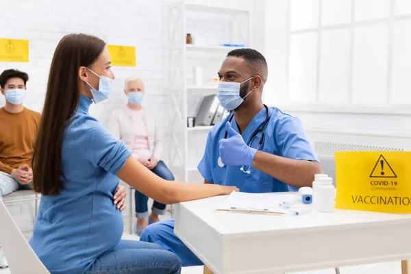 Médico en máscara que sugiere pulgares hacia arriba para el paciente vacunado en el hospital — Foto de Stock