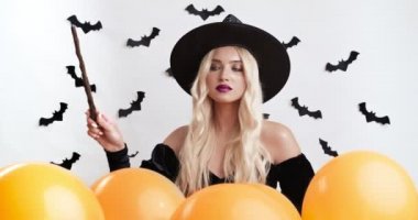 Sihirli değnekle sihirbazlık yapan, kameraya işaret eden kendinden emin genç büyücü.