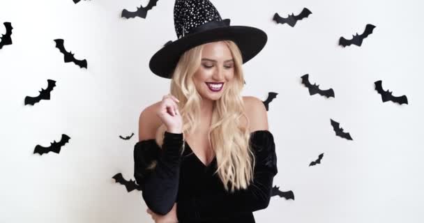 Mladá hravá blondýnka dáma v kouzelnice halloween kostým ukazující mlčení gesto s prstem a zkřížené ruce — Stock video