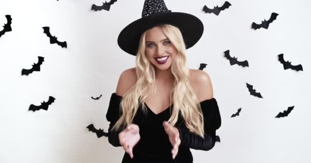 Crazy young witch woman in black halloween costume evil laughing, rubbing hands and looking at camera — Stock Video
