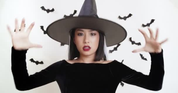 Asiatisk kvinna i svart häxa kostym gjutning spell till kameran, Halloween magi koncept — Stockvideo