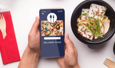 Sağlıklı yemek teslimatı ve modern aletler. Çevrimiçi yemek sipariş uygulaması olan akıllı telefonu tutan erkek eller