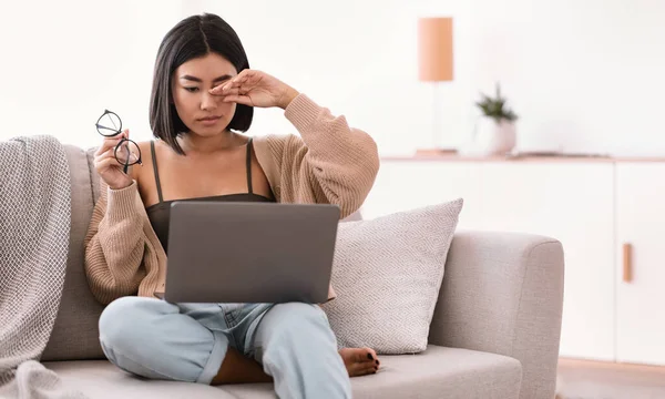 Tired asian lady rubbing her eye using laptop — Stock Photo, Image