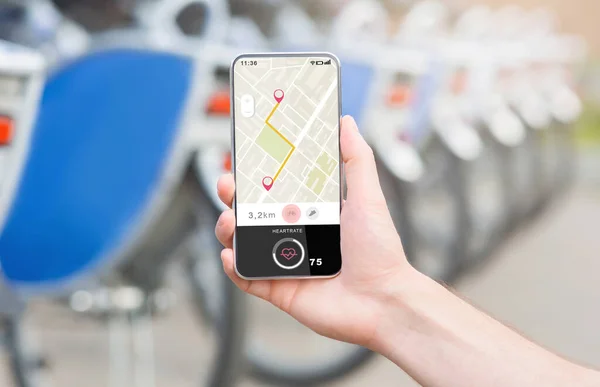 Aplicaciones modernas para el viaje en bicicleta. La mano masculina sostiene el teléfono inteligente con la ruta de navegación GPS en el mapa — Foto de Stock