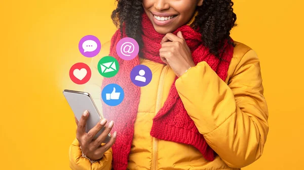 노란 배경 위에 소셜 미디어를 사용하는 스마트 폰을 가진 아프리카 여성 — 스톡 사진