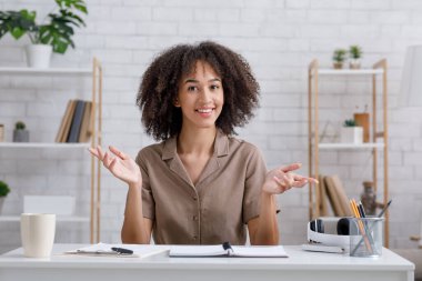 Giyin, ders ver, blog yaz ve ders al. Mutlu Afrikalı Amerikalı kadın el kol hareketi yapıyor ve kameraya bakıyor.