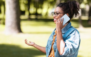 Parkta cep telefonuyla konuşan Afrikalı kadın.