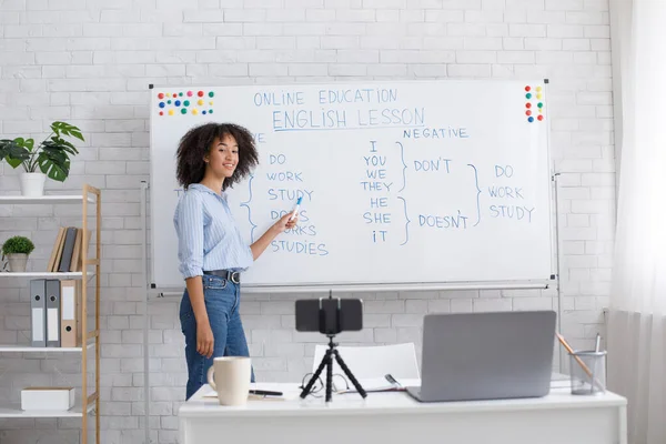 Educación en línea y lección de inglés. Amistosa mujer afroamericana señala pizarra —  Fotos de Stock