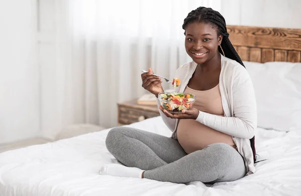 Здорове харчування вагітності. Щаслива вагітна афроамериканка їсть свіжий овочевий салат — стокове фото