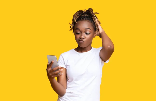 Femme afro-américaine confondue regardant l'écran de téléphone mobile — Photo