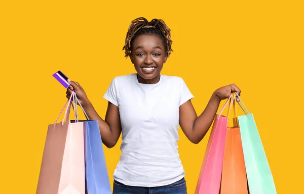 Happy black lady with shopping bags and credit card