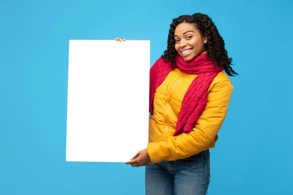 Africano signora mostrando bianco poster pubblicità inverno offerta, sfondo blu — Foto Stock