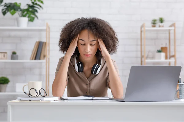 Overwerken en ontspannen terwijl je online werkt of thuis studeert. Moe Afro-Amerikaanse vrouw deed koptelefoon af — Stockfoto