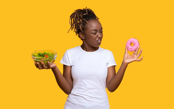 African american woman looking at with disgust at donut