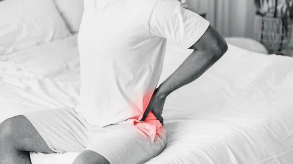 Irriconoscibile uomo nero che soffre mal di schiena dolore seduto a letto all'aperto — Foto Stock