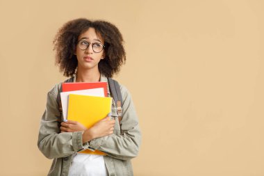 Üzüntü ve yorgunluğun doğal insani duyguları. Yorgun Afrikalı Amerikalı öğrenci not defterlerine sarılıyor.