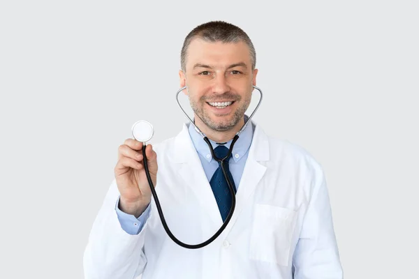 Портрет зрілого лікаря, який посміхається і вказує в просторі копіювання — стокове фото