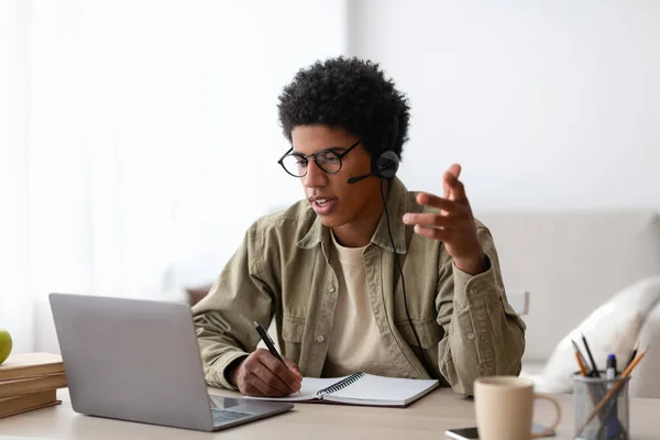 Інтернет-спілкування та концепція освіти. Серйозний чорний студент розмовляє зі своїм вчителем на ноутбуці з дому — стокове фото