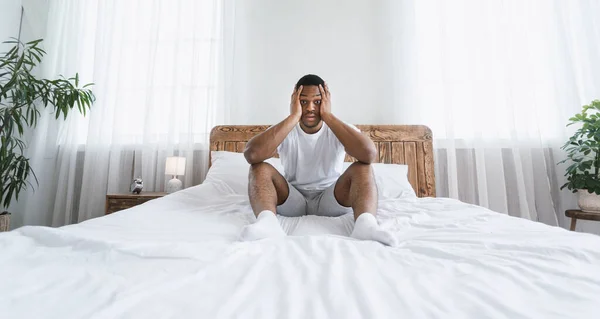 Estressado adormecido afro-americano homem sentado na cama em casa — Fotografia de Stock