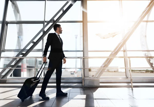 Empresário caminhando pelo terminal do aeroporto, olhando pela janela — Fotografia de Stock