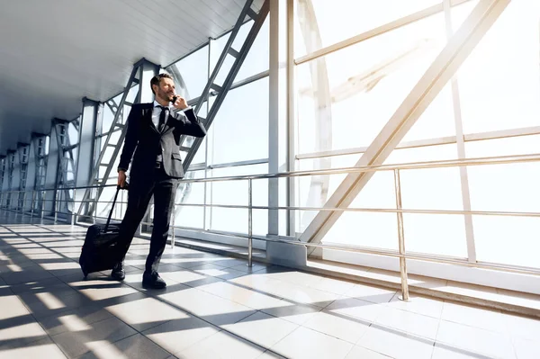 Empresario guapo de mediana edad caminando por el aeropuerto, hablando por teléfono — Foto de Stock