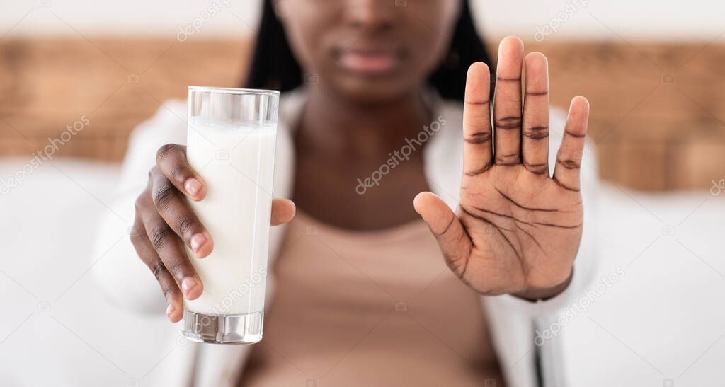 Black Pregnant Lady Rejecting Glass Of Milk, Showing Stop Gesture At Camera