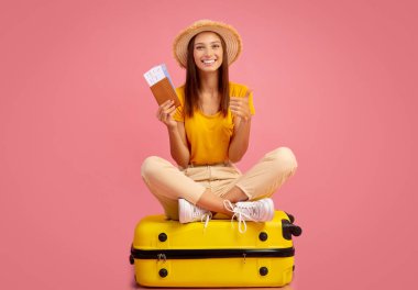 Pembe stüdyo arka planında poz veren neşeli bayan, tatile hazır.