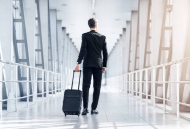 Havaalanı terminalinde yürüyen uzun boylu iş adamının arka görüntüsü