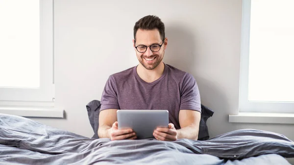 Человек с помощью цифрового планшета просмотр фильма онлайн сидит в спальне — стоковое фото