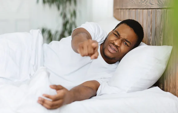 Disturbed Sleepy Man Pointing Finger At Camera Lying In Bedroom