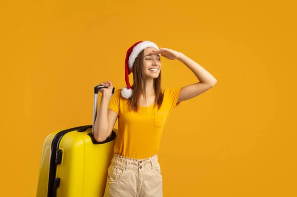 Glimlachende vrouw reiziger met Santa hoed dragen koffer — Stockfoto