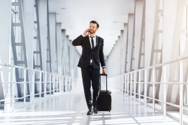 Reicher gutaussehender Unternehmer mit Koffer läuft am Flughafen vorbei — Stockfoto