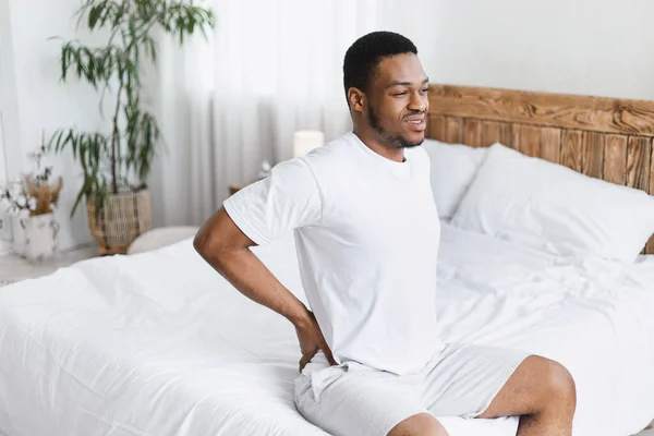 African American Man Touching Aching Back Sitting In Bed Indoors — Stock Photo, Image