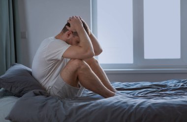 Mutsuz adam depresyon geçiriyor Başı dokunuyor Yatakta Oturuyor