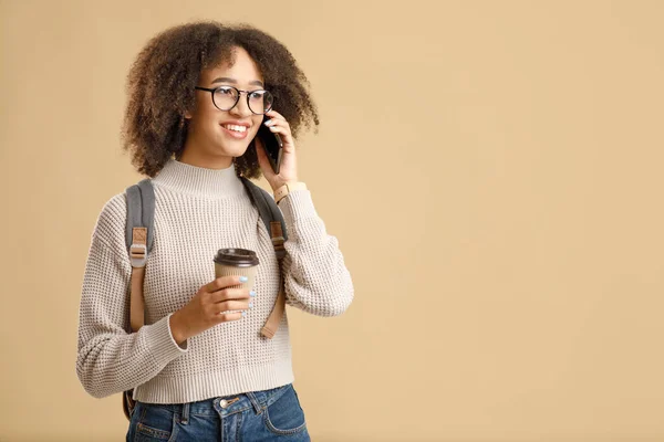 Boldog afro-amerikai hölgy szemüvegben, elvitelre szánt kávéval telefonon beszél. — Stock Fotó
