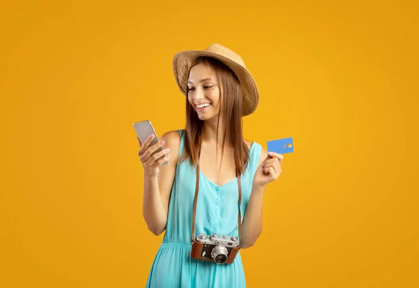 Felice turista donna con smartphone e carta di credito su giallo — Foto Stock