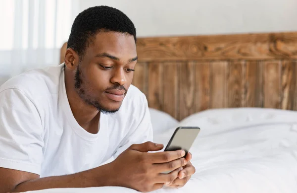 Schwerer Schwarzer benutzte Handy, das im Bett lag — Stockfoto