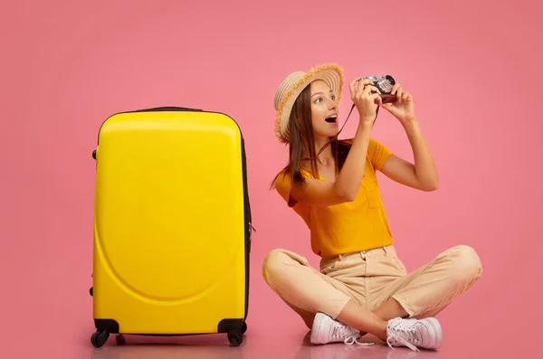 Glückliche Frau fotografiert vor der Kamera und sitzt neben Gepäck — Stockfoto