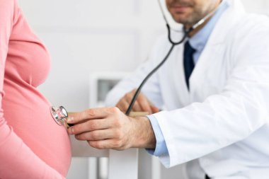 Deneyimli bir doktor hamile bir kadını muayene ediyor.