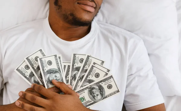 Afrikalı Adam elinde para tutarak uyuyor. Evde yatakta yatıyor. — Stok fotoğraf