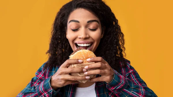 Hambrienta afroamericana dama comiendo hamburguesa en estudio — Foto de Stock