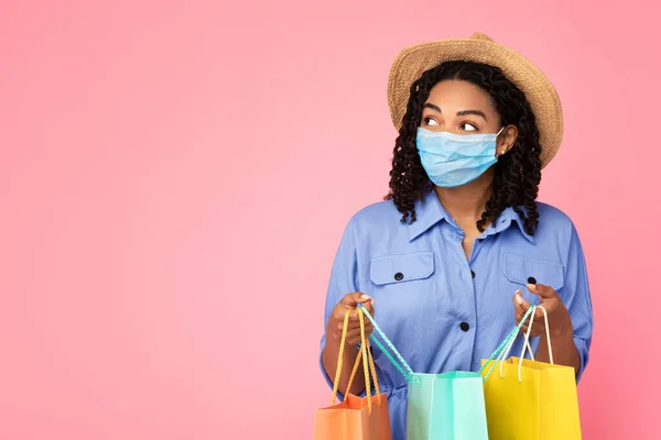 Afrikaanse dame doet het winkelen dragen van masker Holding Bags, Roze achtergrond — Stockfoto